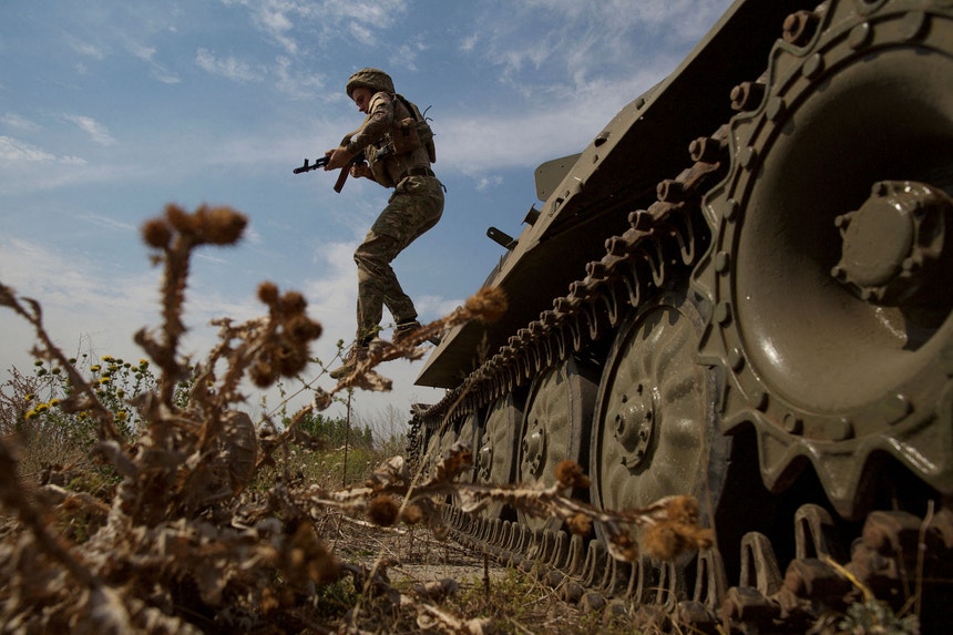 Um militar ucraniano salta de um carro armado 
