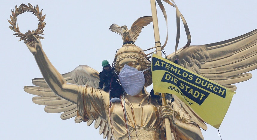 Ambientalistas da Greenpeace colocam uma máscara em estátua em Berlim, contestando o aumento da poluição no ar.
