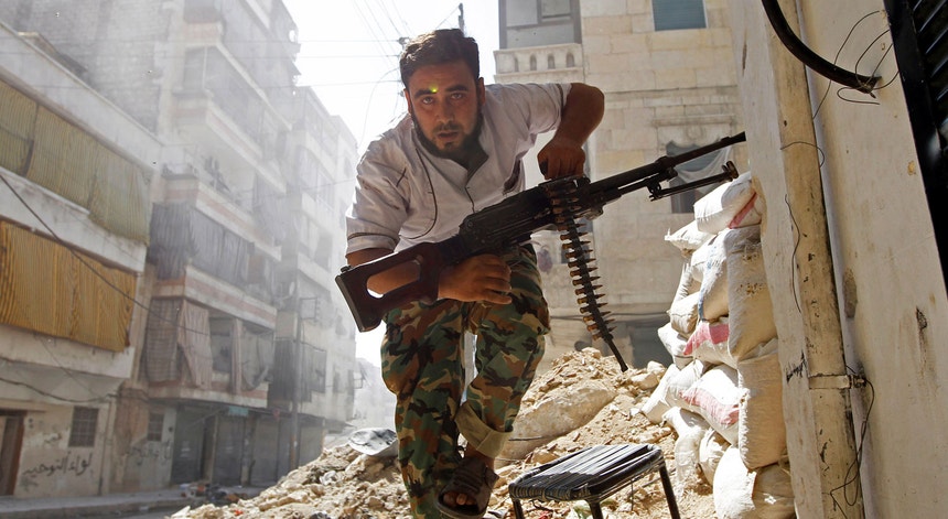 Um combatente do Exército Síria Livre, opositor de Bashar al-Assad procura um esconderijo durante confrontos com o exército sírio no bairro de Salahedin em agosto de 2012

