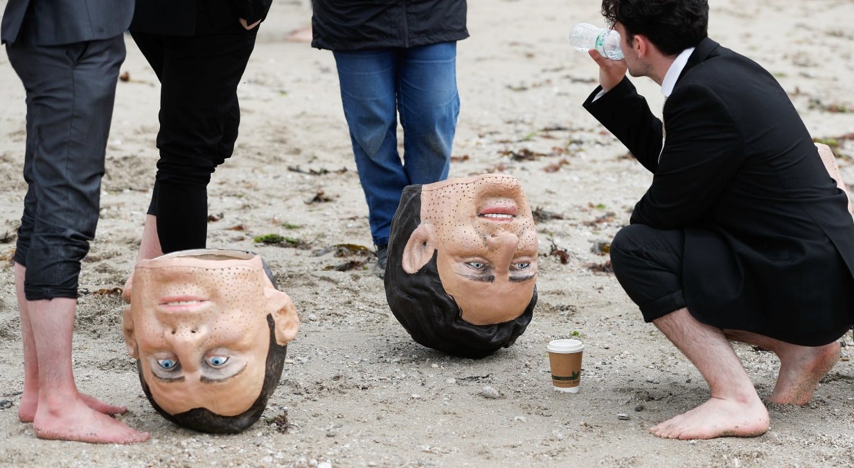  Ativistas da Oxfam est&atilde;o ao lado dos 'cabe&ccedil;udos' , caricaturas do presidente da Fran&ccedil;a Emmanuel Macron e do primeiro-ministro do Canad&aacute;, Justin Trudeau, durante um protesto em uma praia perto de Falmouth | Peter Nicholls - Reuters 