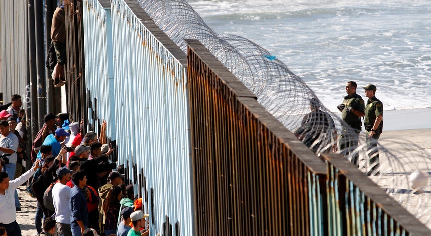 Frente a frente entre migrantes e guardas norte-americanos, junto à cerca que separa o México e os Estados Unidos em Tijuana
