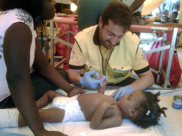  Ajuda chega a quem mais precisa. Um m&eacute;dico espanhol presta assist&ecirc;ncia a uma crian&ccedil;a de 2 anos 