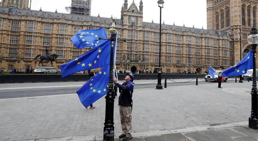Um manifestante anti-Brexit coloca bandeiras da União Europeia junto ao Parlamento britânico, em Londres
