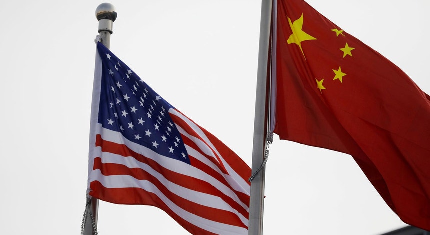 Bandeiras dos Estados Unidos da América e da China, à porta do edifício sede de uma multinacional norte-americana em Pequim, em fevereiro de 2021
