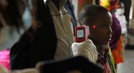 Um agente de emigra&ccedil;&atilde;o nigeriano mede a temperatura corporal de um rapaz no aerporto de Abuja, com um term&oacute;metro digital de laser, com parte das medidas contra a dissemina&ccedil;&atilde;o do &Eacute;bola