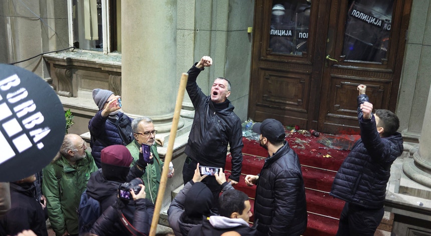 O líder da oposição Aleksandar Jovanovic Cuta gesticula enquanto a polícia cobre a porta do lado de dentro da Câmara Municipal, durante um protesto de apoiantes do partido da oposição Sérvia Contra a Violência (SPN)
